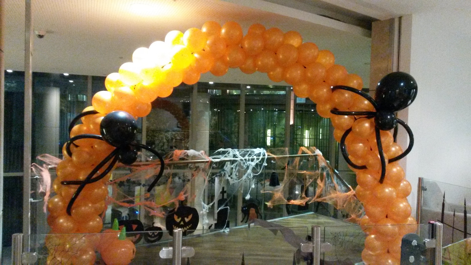 Orange Spiral Balloon Arch with Spider Balloons created for a Halloween Party