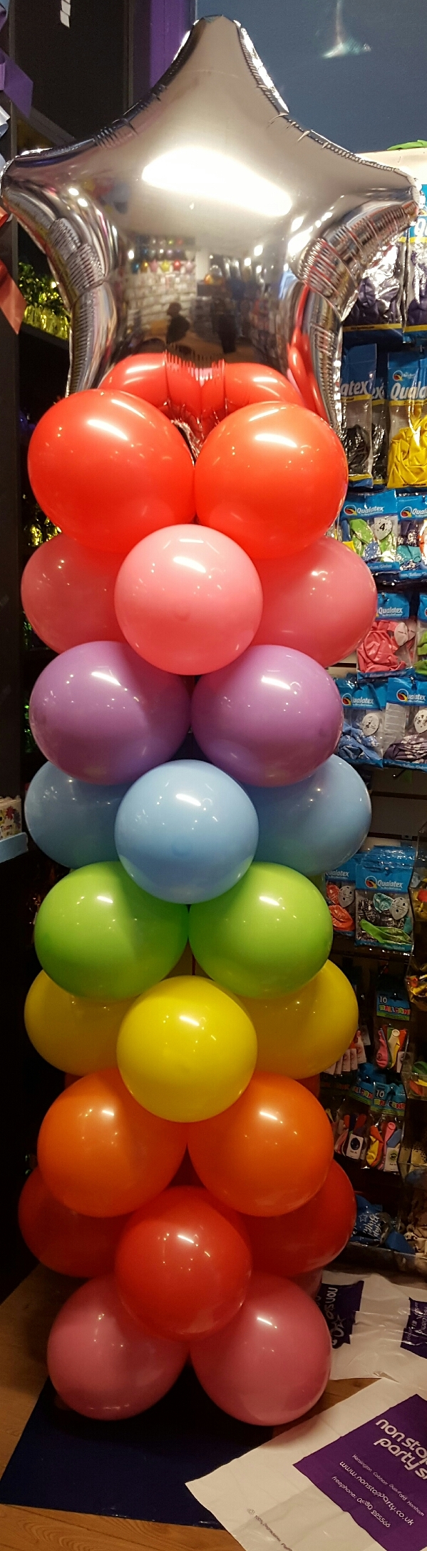 Multi-coloured column topped with a jumbo silver star foil balloon
